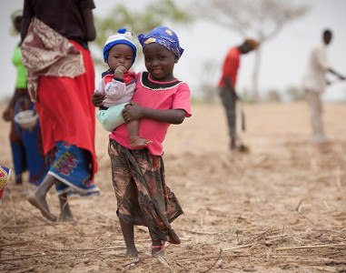 young African girl smiling and holding baby